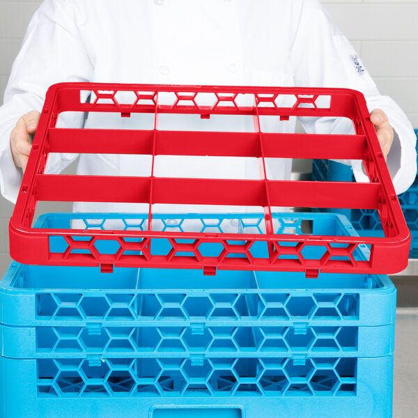 A chef holding a red plastic shelf with blue and red trays.
