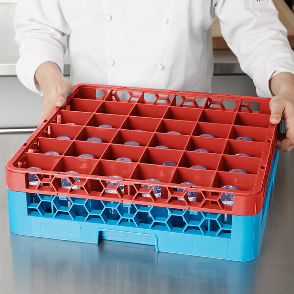 A person in a white coat holding a red Carlisle glass rack extender with 36 compartments.