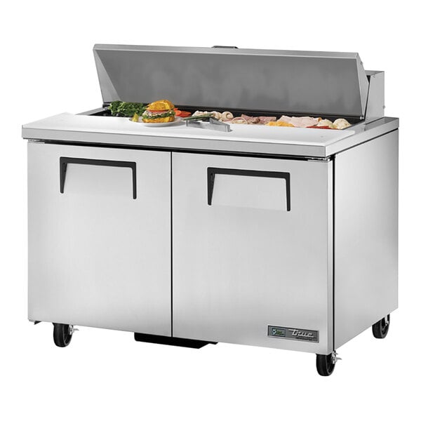 A True 2 door refrigerated sandwich prep table on a counter with food inside.
