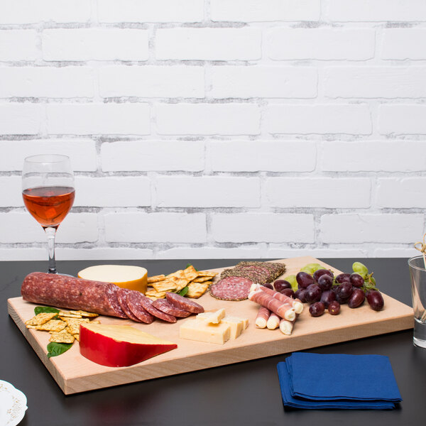 A Vollrath hardwood display cutting board with meat, cheese, and wine on it.