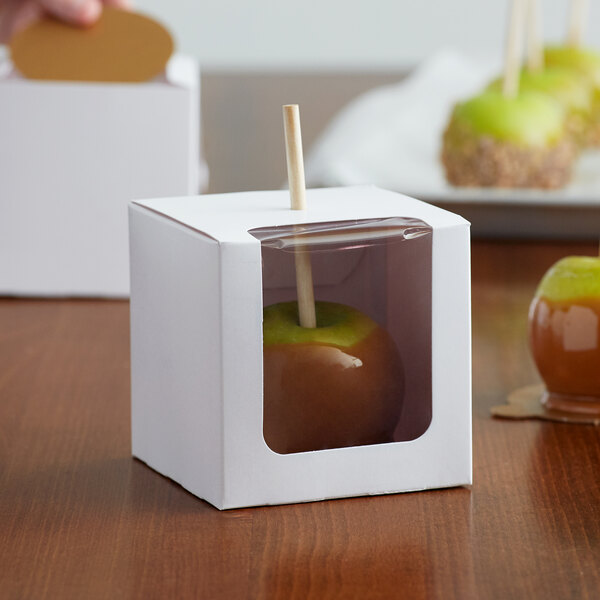 A Baker's Mark white candy apple box with a window holding a green caramel apple.