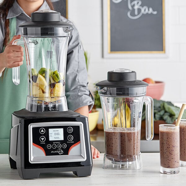 A woman using an AvaMix commercial blender to make a fruit smoothie.