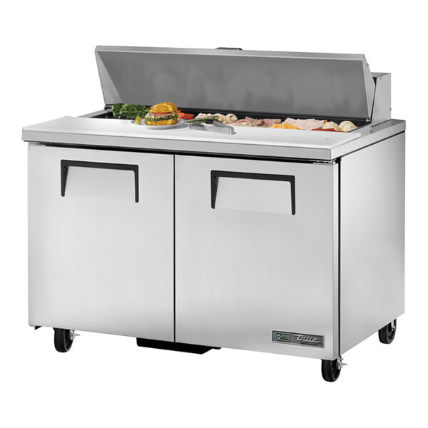 A True stainless steel refrigerated sandwich prep table with two large doors on a counter.