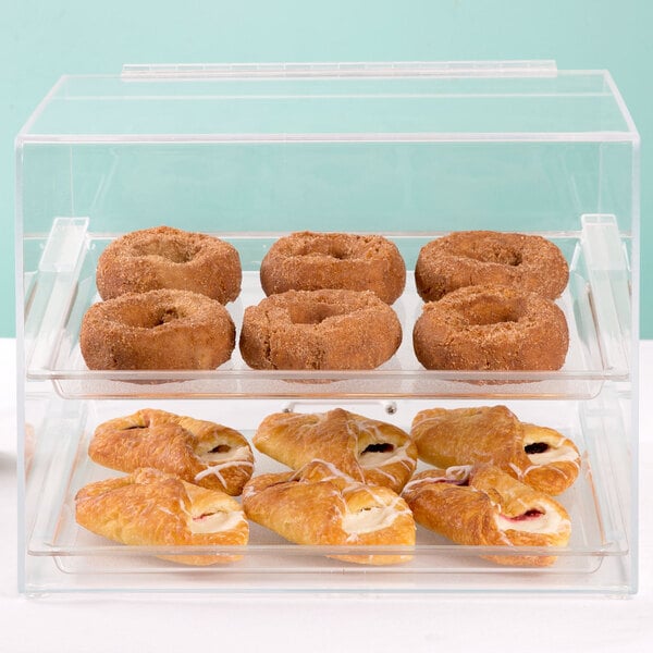 A Cal-Mil clear acrylic display case with donuts and pastries on a counter.