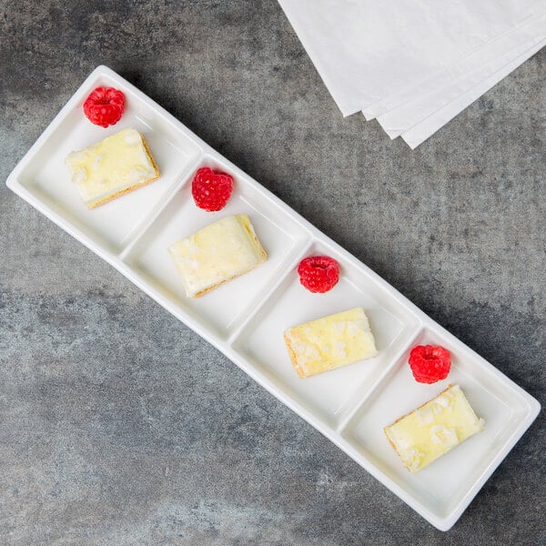 A white Libbey porcelain rectangular tray with four slices of cake with raspberries on top.