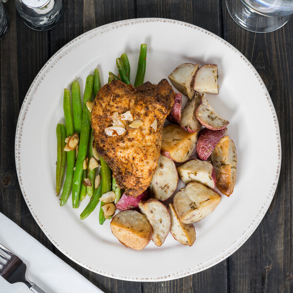 A Libbey Farmhouse porcelain plate with chicken, potatoes, and green beans on a table.