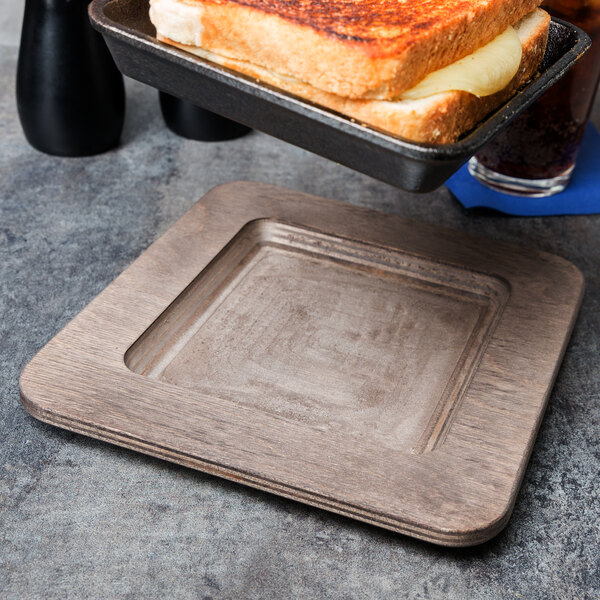 A toasted sandwich on a Lodge square wood underliner on a tray.