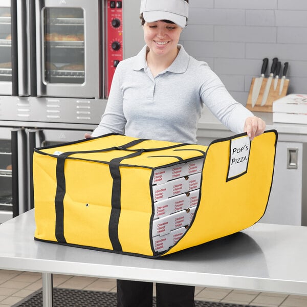 A woman holding a yellow Choice insulated pizza delivery bag with white pizza boxes inside.