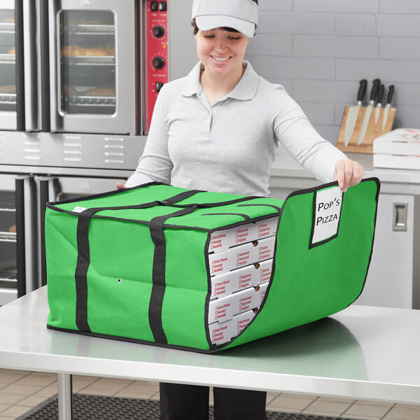 A woman holding a green Choice insulated pizza delivery bag with white pizza boxes inside.