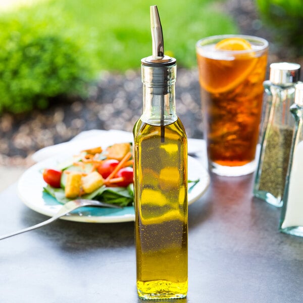 A Tablecraft olive oil cruet on a table next to food.