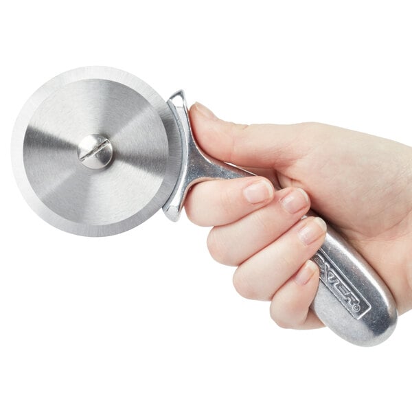 A hand using a Dexter-Russell aluminum handle pizza cutter to slice a pizza.
