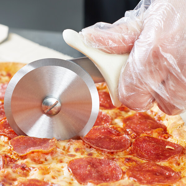 A person using a Dexter-Russell pizza cutter to slice a pizza.