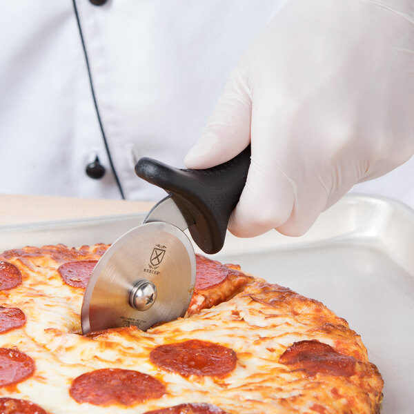 A person in a white glove using a Mercer Culinary pizza cutter to cut a pizza.