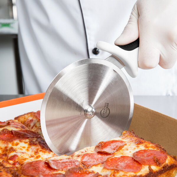 A person using a Mercer Culinary pizza cutter to cut a pizza.