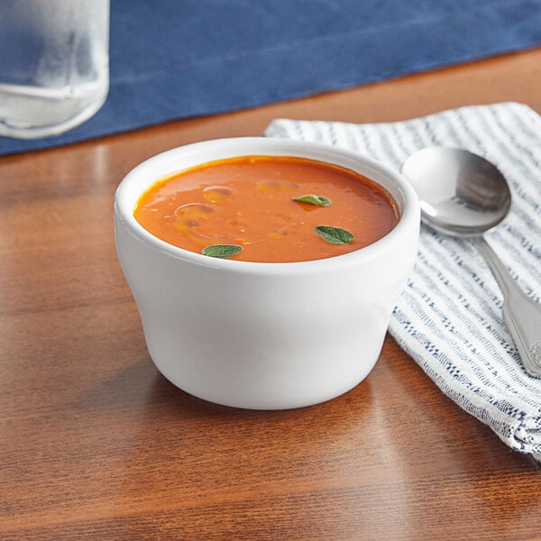 A bowl of soup with a spoon on a table.