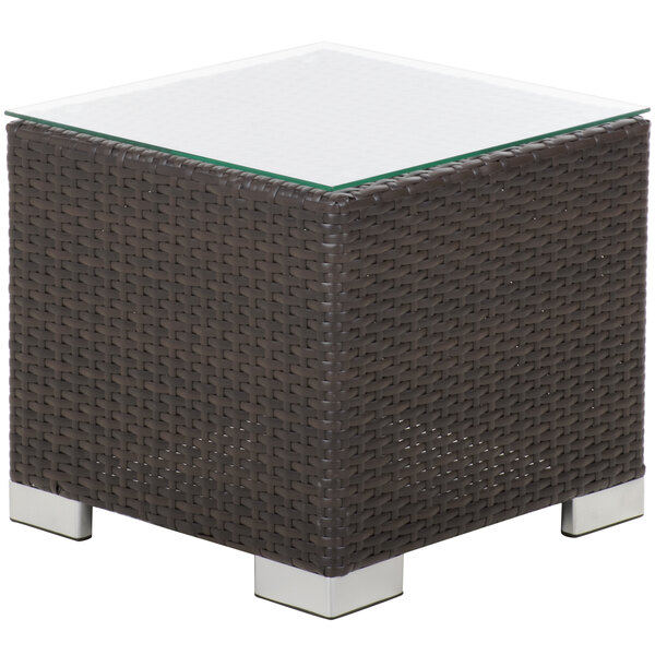 A BFM Seating square wicker end table with glass top.