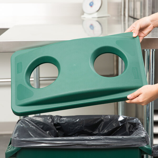 A woman using a green Rubbermaid Slim Jim recycling bin with a green lid.