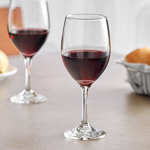 Two Acopa wine glasses on a table with a glass of red wine