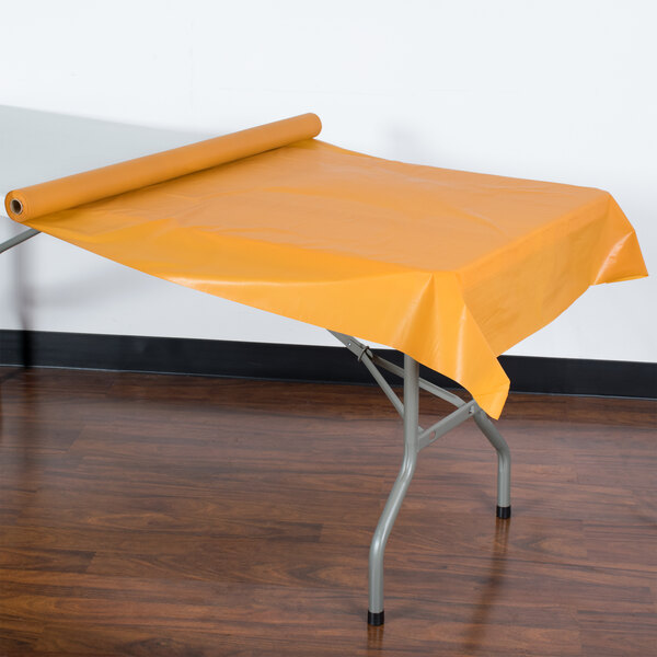 A table with a yellow plastic tablecloth on it.