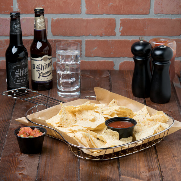 A Clipper Mill guitar basket filled with chips and a bowl of salsa on a table.