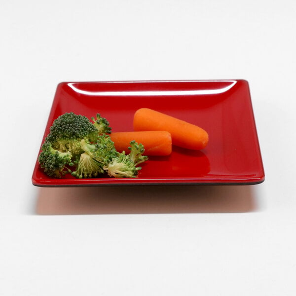 A red and black square Elite Global Solutions Karma melamine plate with broccoli and carrots on it.