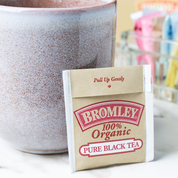 A cup of tea next to a packet of Bromley Organic Black Tea.