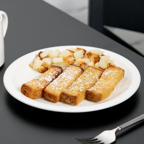 A Libbey round white porcelain plate with french toast, powdered sugar, and coffee on a table.
