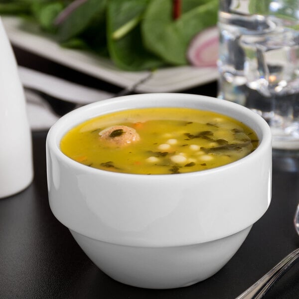 A Libbey white porcelain bouillon bowl filled with soup on a table.