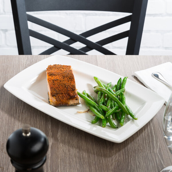 A plate of food with green beans and a fork on a white rectangular Libbey porcelain plate.