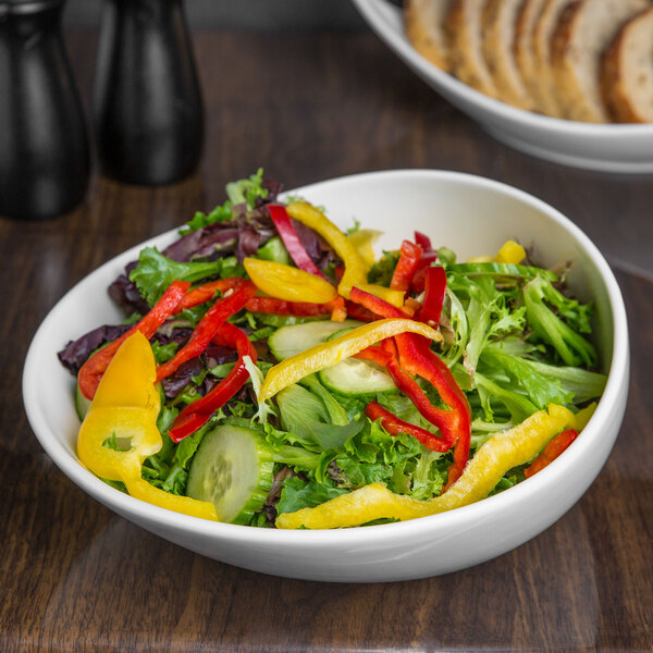 A close up of a bowl of salad with peppers and cucumbers.