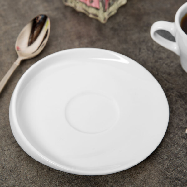 A white porcelain saucer with a cup of coffee on a table.