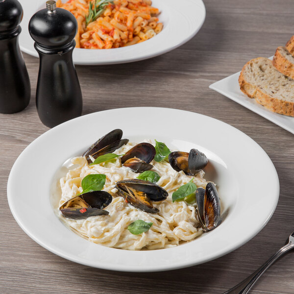 A table set with a Libbey Royal Rideau white porcelain bowl filled with pasta, mussels, and basil.