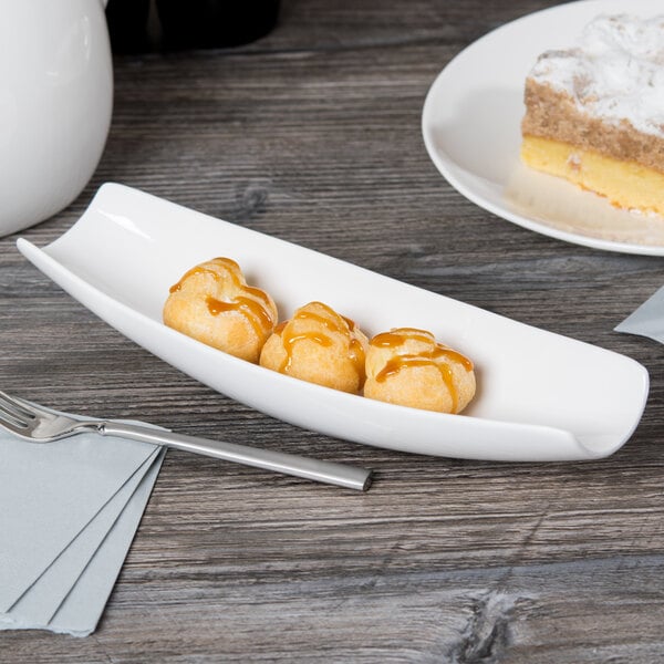 A white Libbey canoe plate with dessert on a table.