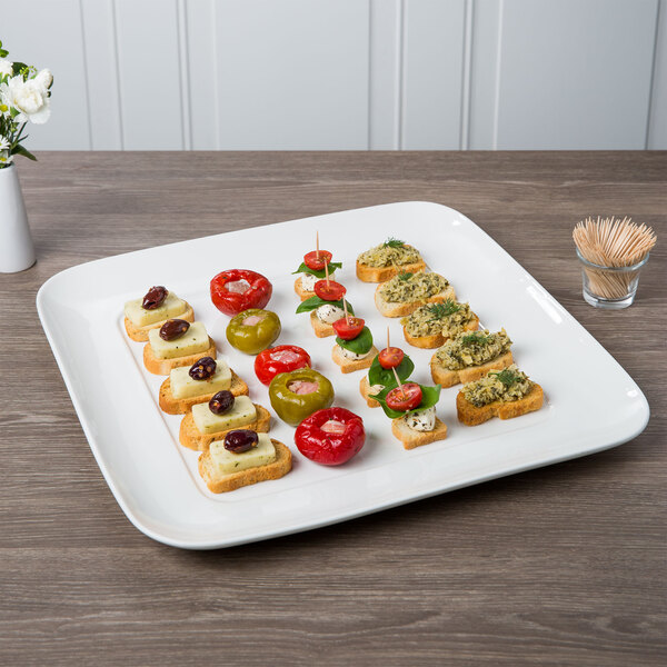 A Libbey square white porcelain tray with appetizers on it.
