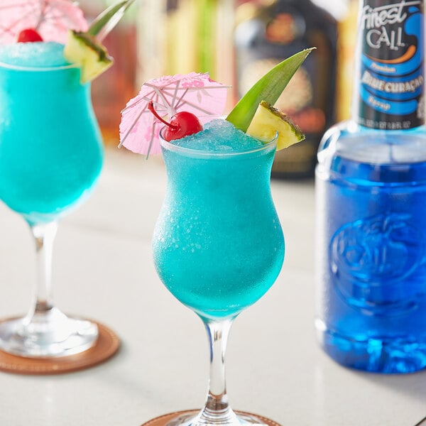 A blue drink with a fruit and umbrella garnish served in a glass of Finest Call Premium Blue Curacao Syrup.