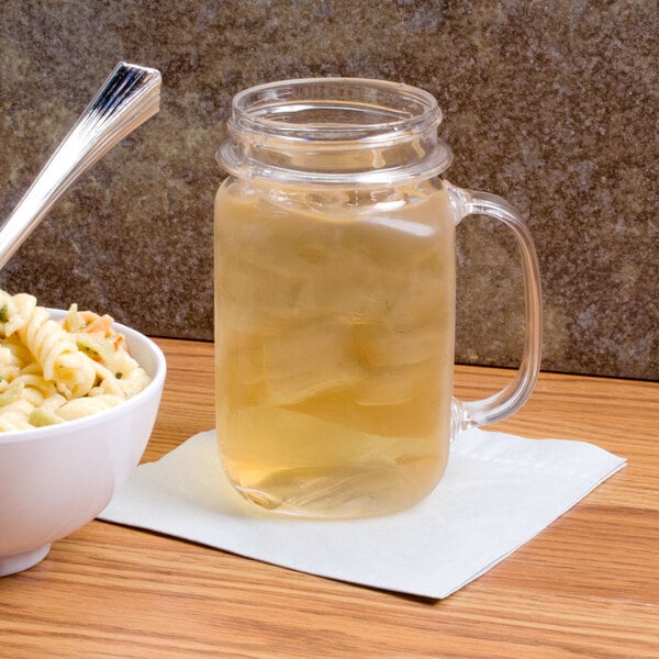 A GET customizable plastic mason jar filled with a clear liquid next to a bowl of macaroni and cheese.