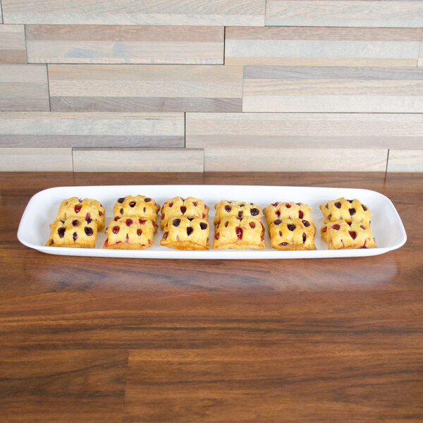 A white Sabert rectangular catering tray with a group of pastries on a table.