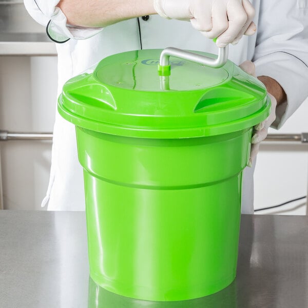 A person in white gloves using a green Choice Prep salad spinner.