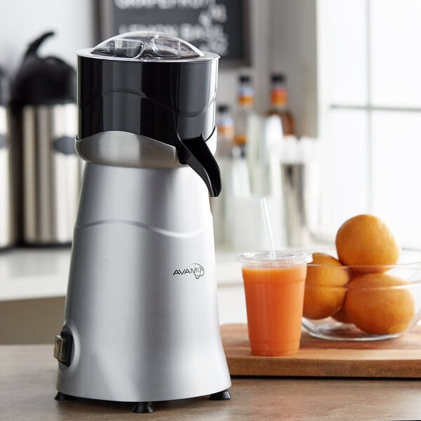 An AvaMix citrus juicer on a counter with a bowl of oranges.