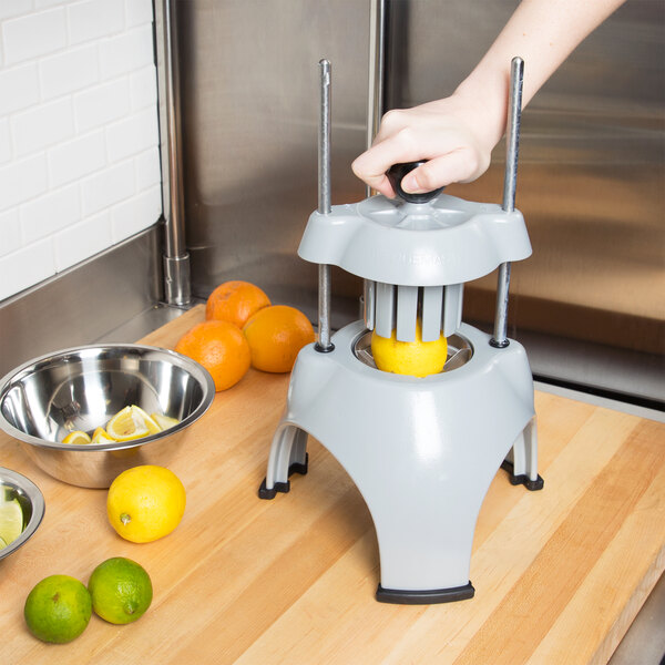 A person using a Vollrath Wedgemaster to juice a lemon.