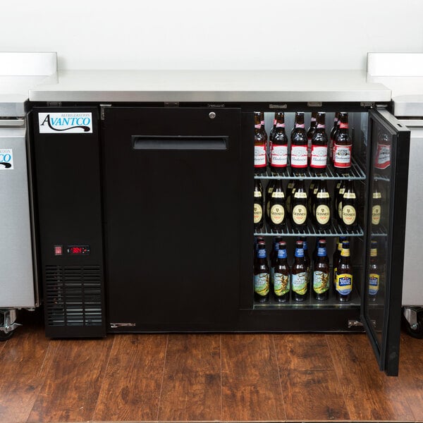 An Avantco black back bar refrigerator filled with bottles of beer.