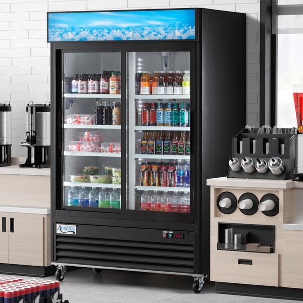 An Avantco black sliding glass door merchandiser refrigerator with drinks on shelves.