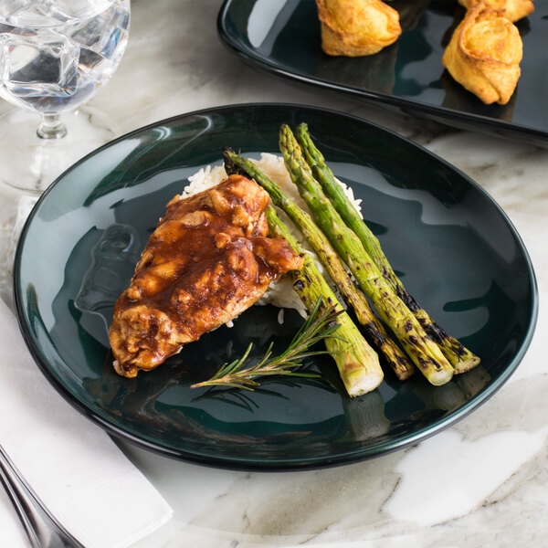 A GET green melamine coupe plate with chicken and asparagus on it.