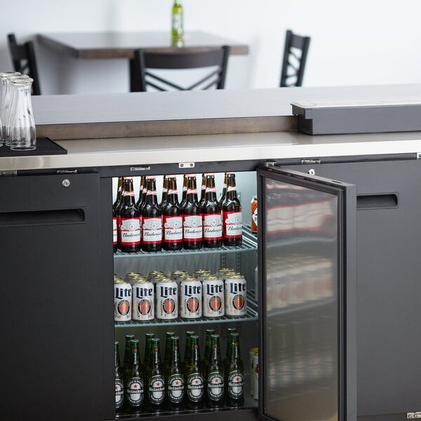 An Avantco black back bar refrigerator with beer bottles inside.