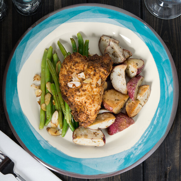 A Kanello Diamond Ivory melamine plate with chicken, potatoes, and green beans on a table.