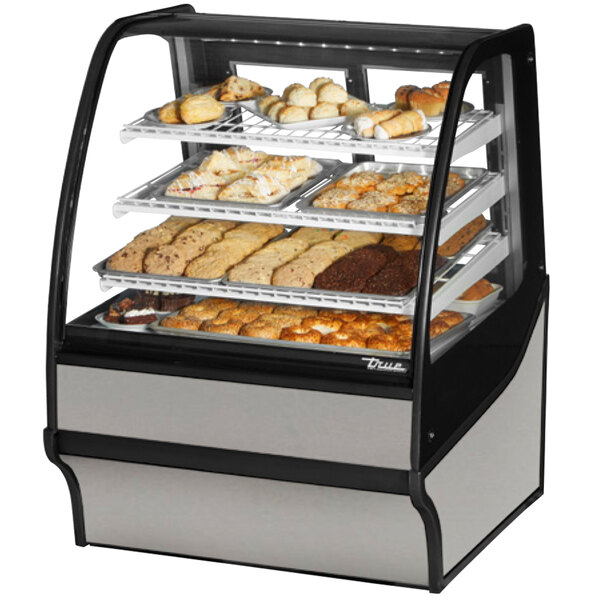 A True curved glass stainless steel dry bakery display case on a counter filled with various pastries.
