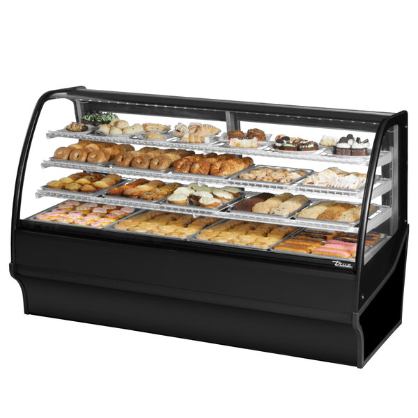 A True curved glass black dry bakery display case on a counter filled with different types of pastries.