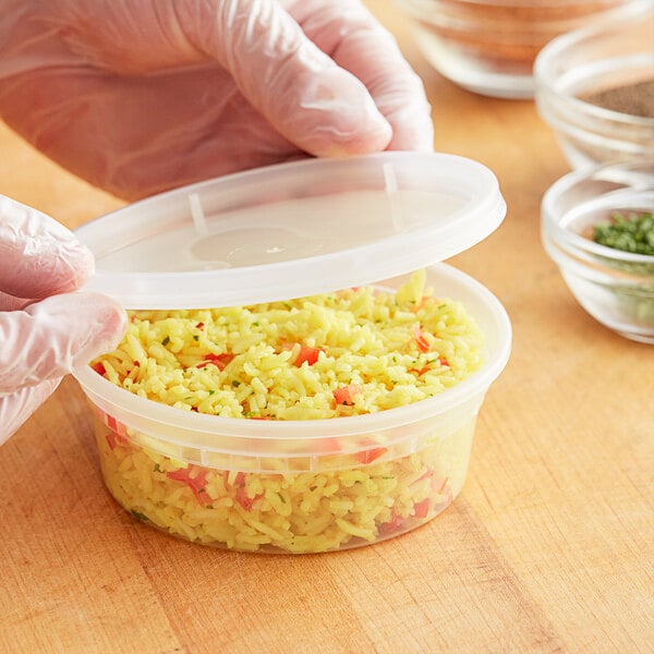 A person holding a ChoiceHD translucent plastic deli container filled with rice.