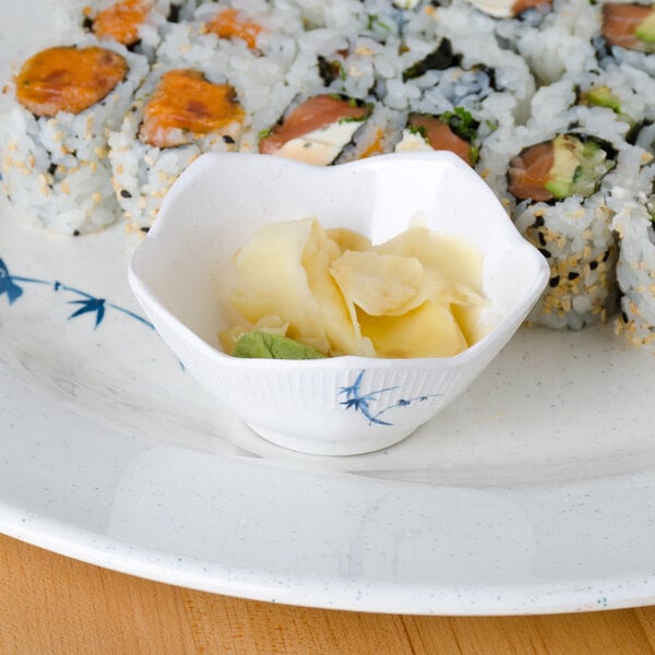 A plate of sushi with a small bowl of sauce on a Thunder Group Blue Bamboo dish.