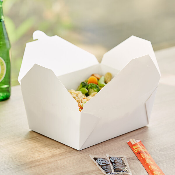 A white Choice paper take-out box of food on a table.